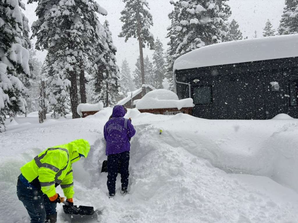 EN Tahoe Property Care crew shoveling deep snow at a cabin during a snowstorm