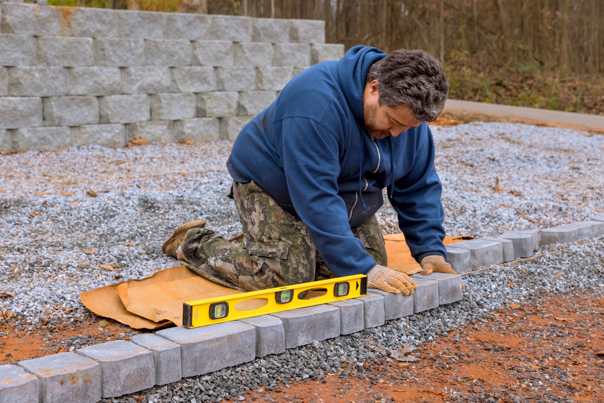 Landscaper leveling concrete pavers with a spirit level during installation